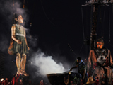 在努嘉人举行的一个燃烟仪式中，两个“巨人”的脸部被画上了油彩，这是传统欢迎仪式的一部分。珀斯国际艺术节，Toni Wilkinson摄
